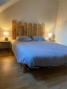 um quarto com uma cama grande e uma grande cabeceira em madeira em maison des résidences de la mer em Courseulles-sur-Mer