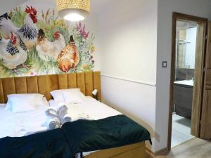 1 dormitorio con 1 cama con una pintura de pollo en la pared en Ranczo Na Sówce en Ciechanowiec