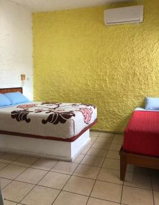 ein Schlafzimmer mit 2 Betten und einer gelben Wand in der Unterkunft Hotel Perla Mazatlan in Mazatlán