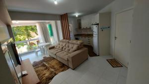 ein Wohnzimmer mit einem Sofa und einer Küche in der Unterkunft RESIDENCIAL BORBOLETAS DO MAR in Bombinhas