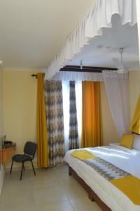 モンバサにあるVienna Apartments-Mombasa, Mtwapaのベッドと椅子と窓のある寝室