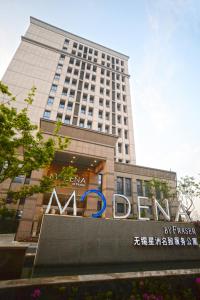 a large building with a sign in front of it at Modena By Fraser New District Wuxi in Wuxi