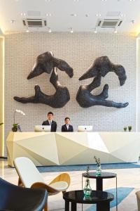 two men sitting at a reception desk in an office with a mural at Modena By Fraser New District Wuxi in Wuxi