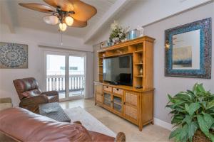 een woonkamer met een bank en een televisie bij Tiki 216 in South Padre Island