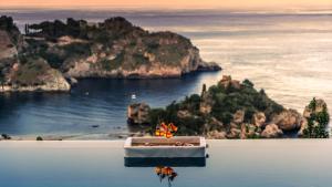a boat in the water with a view of a island at Isola Bella Infinity Suites in Taormina +156 photos