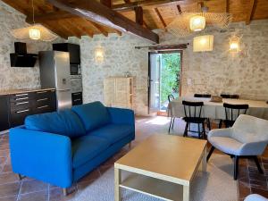 a living room with a blue couch and a table at Le Clos Gallien - Maison coucoute in Illats