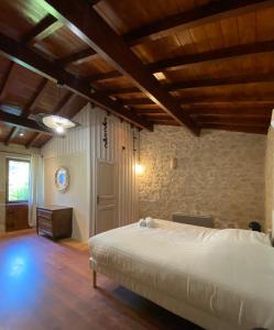 Illats的住宿－Le Clos Gallien - Maison coucoute，卧室配有一张石墙内的大床