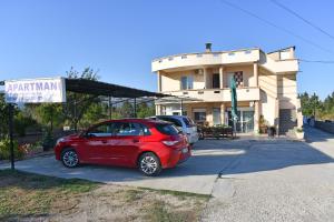 ein rotes Auto, das vor einem Haus parkt in der Unterkunft Apartments Murati in Ulcinj