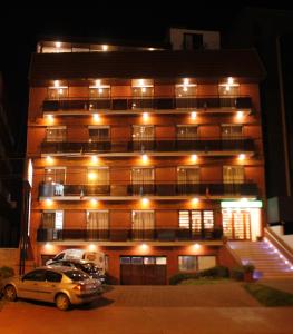 un edificio con coches aparcados delante de él por la noche en Apart Hotel Family en Mar del Plata