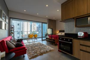 uma sala de estar com um sofá vermelho e uma cozinha em Loft em Moema, próximo ao Metro, com estacionamento no condomínio em São Paulo