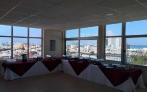 Habitación grande con mesas, sillas y ventanas. en Harbour Inn - Veracruz, en Veracruz