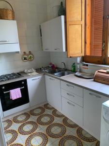 una cucina con armadi bianchi, lavandino e piano cottura di Il mare fuori casa vacanze a Marina di Casalvelino