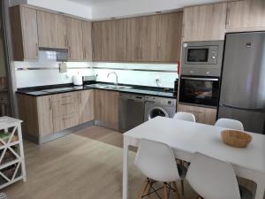 een keuken met houten kasten en een witte tafel en stoelen bij Numar Residence J -Manta Rota in Manta Rota
