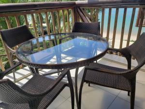 a glass table and chairs on a balcony at Barra Bali - Luxo e Paraiso in Barra de São Miguel