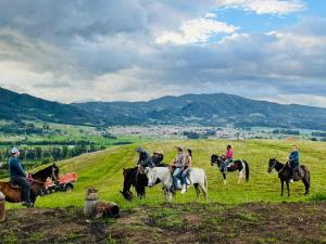 a group of people riding horses in a field at Peñavista. in Simijaca