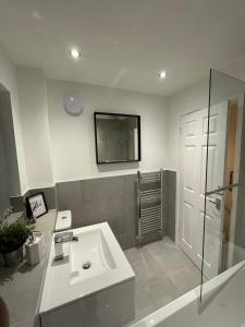 Un baño blanco con lavabo y ducha. en Modern 2 bed house Cannock Driveway for 2 vehicles Perfect for contractors Business Travellers Short Stays Close to M6 M54 i54 A5 A38 McArthur Glen Designer Outlet, en Cannock