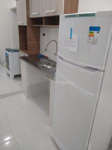 La cuisine est équipée d'un réfrigérateur blanc et d'un évier. dans l'établissement Casa de praia no centro de Caraguatatuba, à Caraguatatuba