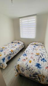 2 camas en un dormitorio con ventana en Amtaya Inmobiliaria, en Iquique