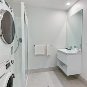 a bathroom with a washing machine and a sink at Quest Takapuna in Auckland