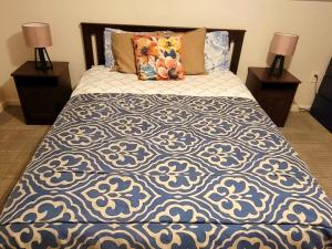 a bed with a blue and white comforter and two lamps at Delightful well located one bedroom attic in Elizabeth
