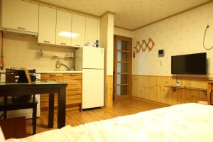 a kitchen with a refrigerator and a table in a room at Jungmun Haesung Parktel in Seogwipo