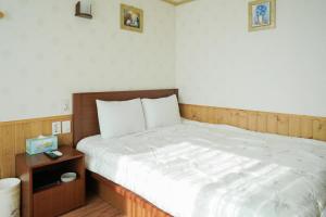 a bedroom with a large bed with a wooden headboard at Jungmun Haesung Parktel in Seogwipo