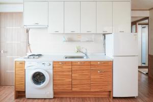 a kitchen with a white refrigerator and a washing machine at Jungmun Haesung Parktel in Seogwipo