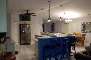 a kitchen with a island with blue bar stools at Del Mar Villa in Naples