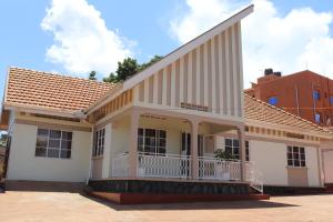 a white house with a balcony on a street at Luwafu Guest House in Kampala