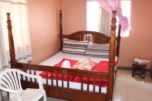 a bedroom with a wooden bed and a white chair at Luwafu Guest House in Kampala