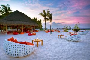 a beach with chairs and tables on the sand at Kuramathi Maldives in Rasdhoo
