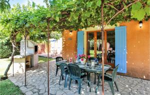 a table and chairs on a patio under a tree at Cozy Home In Carpentras in Carpentras
