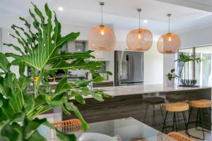 uma cozinha com uma mesa de vidro e luzes pendentes em Escapades @ Palm Cove em Palm Cove