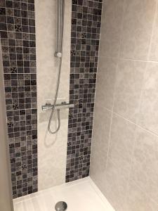 a bathroom with a shower with black and gray tiles at Au cœur du quartier historique in Lannion