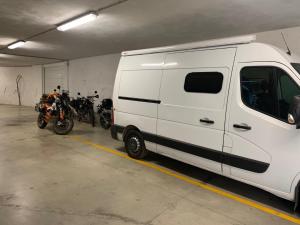 una furgoneta blanca estacionada en un garaje con motocicletas en B&B Eremes, en Cuneo
