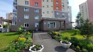 ケメロヴォにあるApartment na Sportivnaya 17/1の花の咲く庭園のある建物