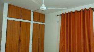 Habitación con armarios de madera y cortinas naranjas. en Start-Up Apartments Nyali, en Nyali 3 fotos más