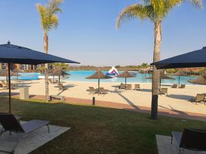 a resort with a pool and palm trees and chairs and umbrellas at The Blyde - Morden 2 bedroom apartment in Pretoria