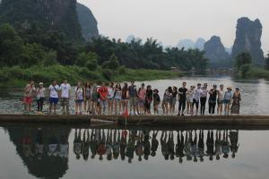 a group of people standing on a raft in the water at Travel light Guilin in Guilin