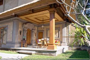 a porch of a house with a table and chairs at Nefatari Exclusive Villas in Ubud