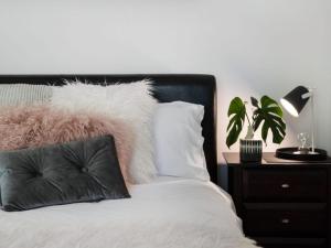 a bed with a pillow and a nightstand with a plant at Cottage 4A in Daylesford