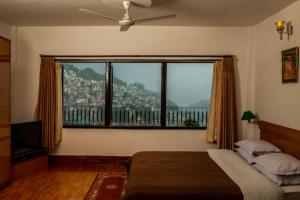 a bedroom with a large window with a view of a city at Rhenock House (a luxury villa) in Gangtok