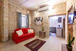 a living room with a red couch and a kitchen at BRG34 - Historical Vittoriosa Townhouse in Vittoriosa