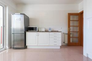 eine Küche mit weißen Schränken und einem Kühlschrank aus Edelstahl in der Unterkunft Expo Delight by Homing in Lissabon