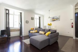 sala de estar con sofá gris y almohadas amarillas en Downtown Madalena by Homing, en Lisboa