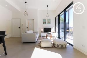 una sala de estar con muebles blancos y ventanas grandes. en Avenida Premium by Homing en Lisboa