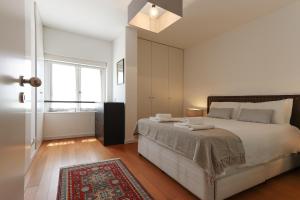 a white bedroom with a large bed and a window at Downtown Chiado by Homing in Lisbon