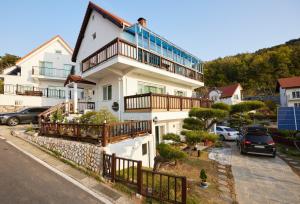 a white house with a balcony and cars parked at Herkules Namhae German Village in Namhae