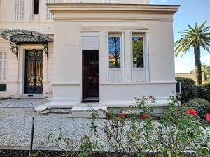 een wit huis met een voordeur en bloemen bij Charmant appartement dans villa avec parc in Cannes