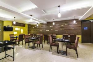 a restaurant with black tables and chairs and yellow walls at Magnus Star Residency in Pune